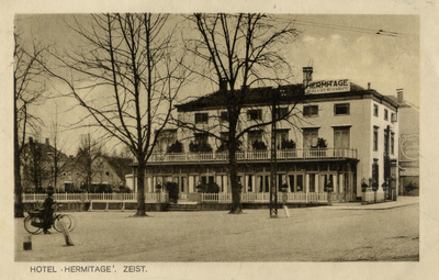 16046 Gezicht op de voor- en rechtergevel van het hotel Hermitage, met enkele loofbomen (Het Rond 7) te Zeist uit het oosten.